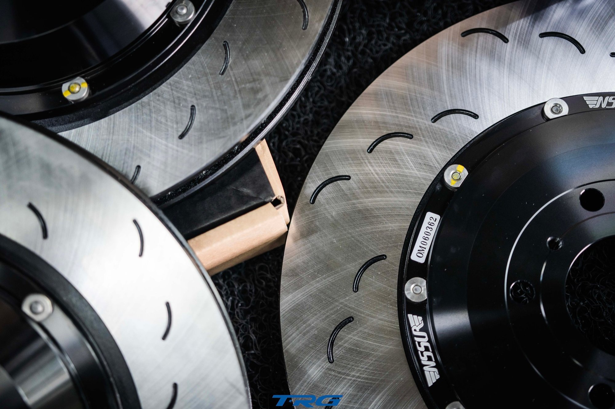 Overhead close up of three Neotech brake discs showing the curved slot pattern on the friction faces