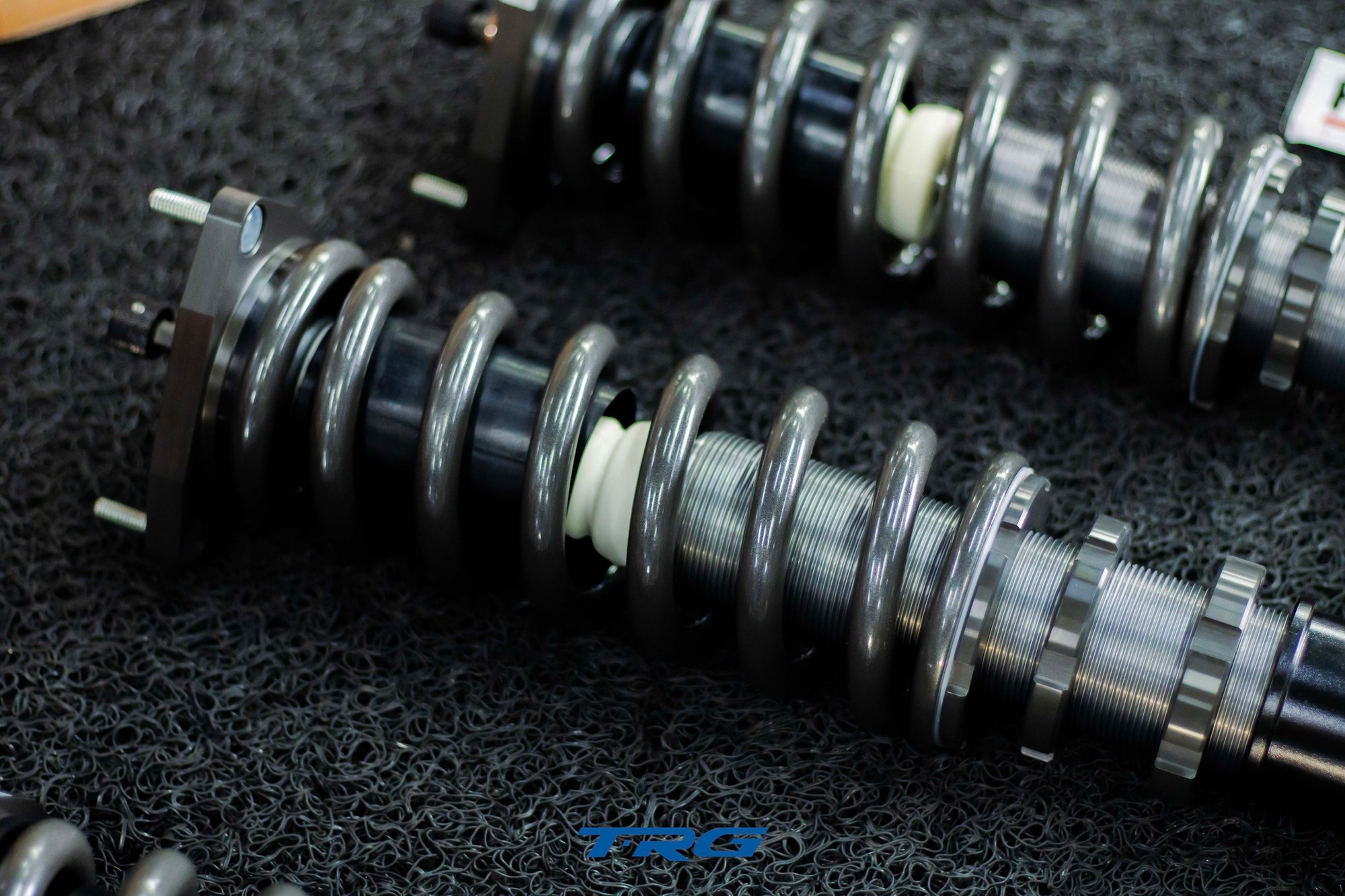 Close up of two Neotech units showing threaded lower body, spring, bump stop and studded top plate