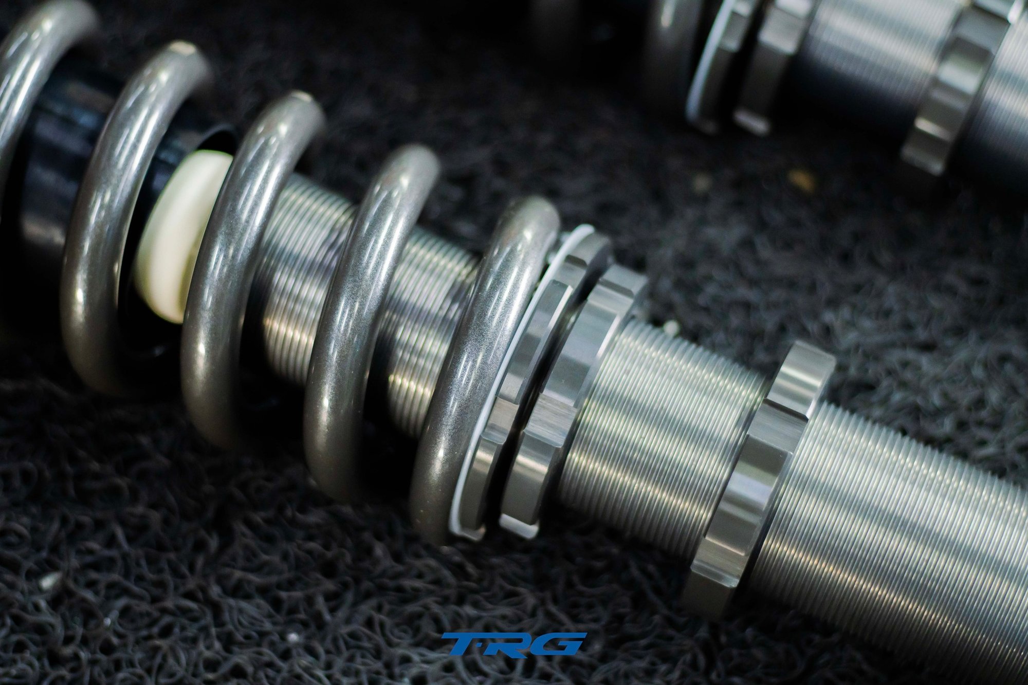 Macro of the threaded damper body with spring perch collars and lock rings for ride height