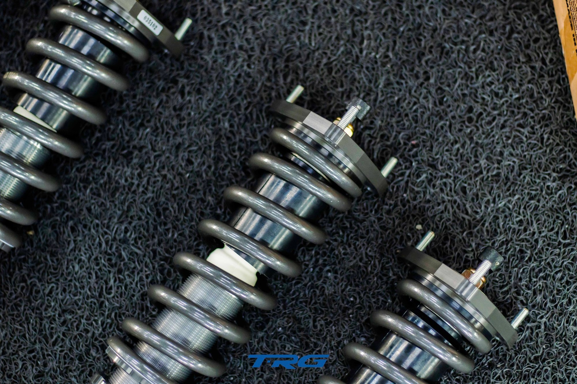 Overhead view of three assembled units showing top mount plates and gold damping adjuster nuts